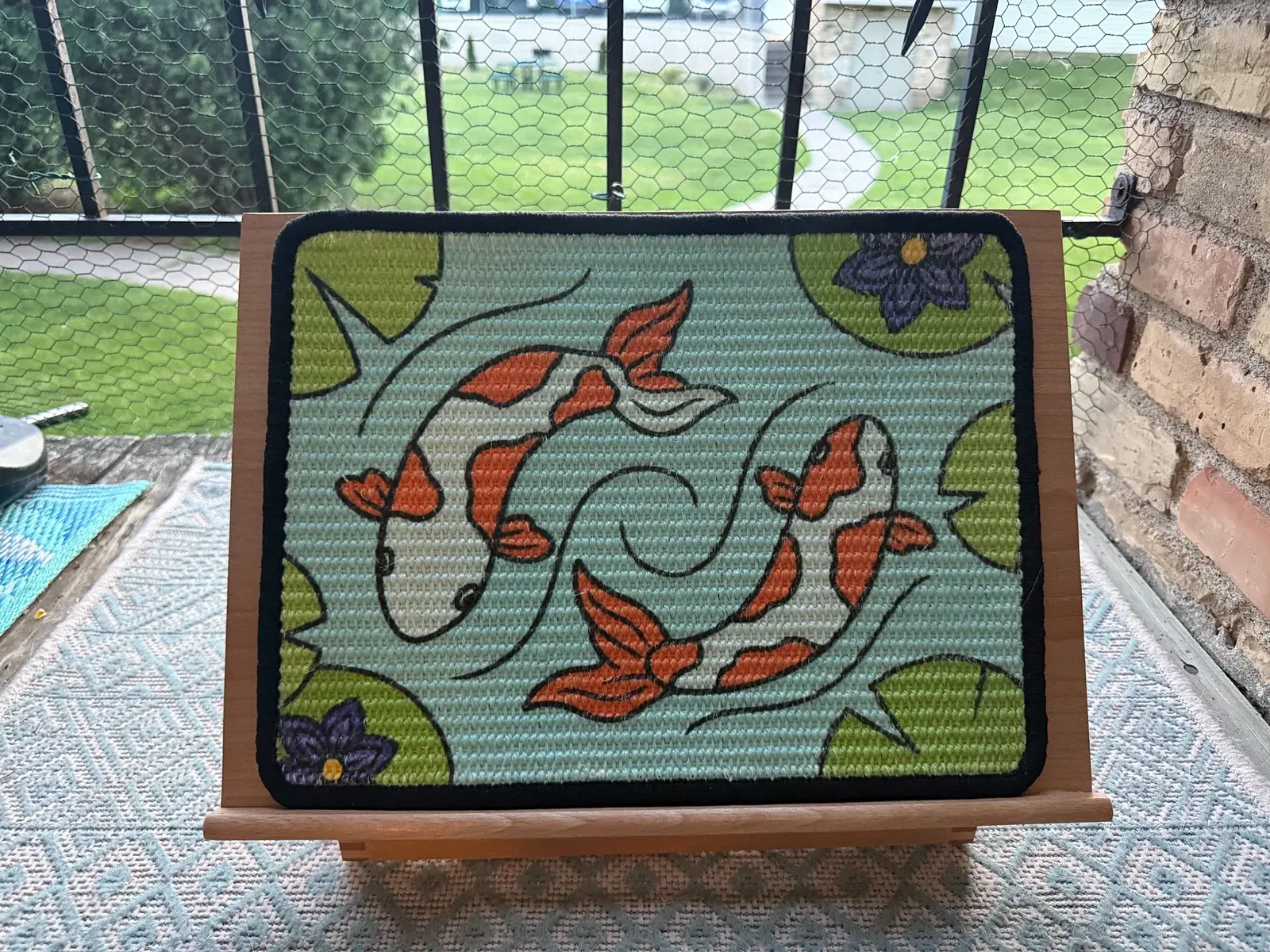 Koi scratch panel displayed upright on a wooden easel.