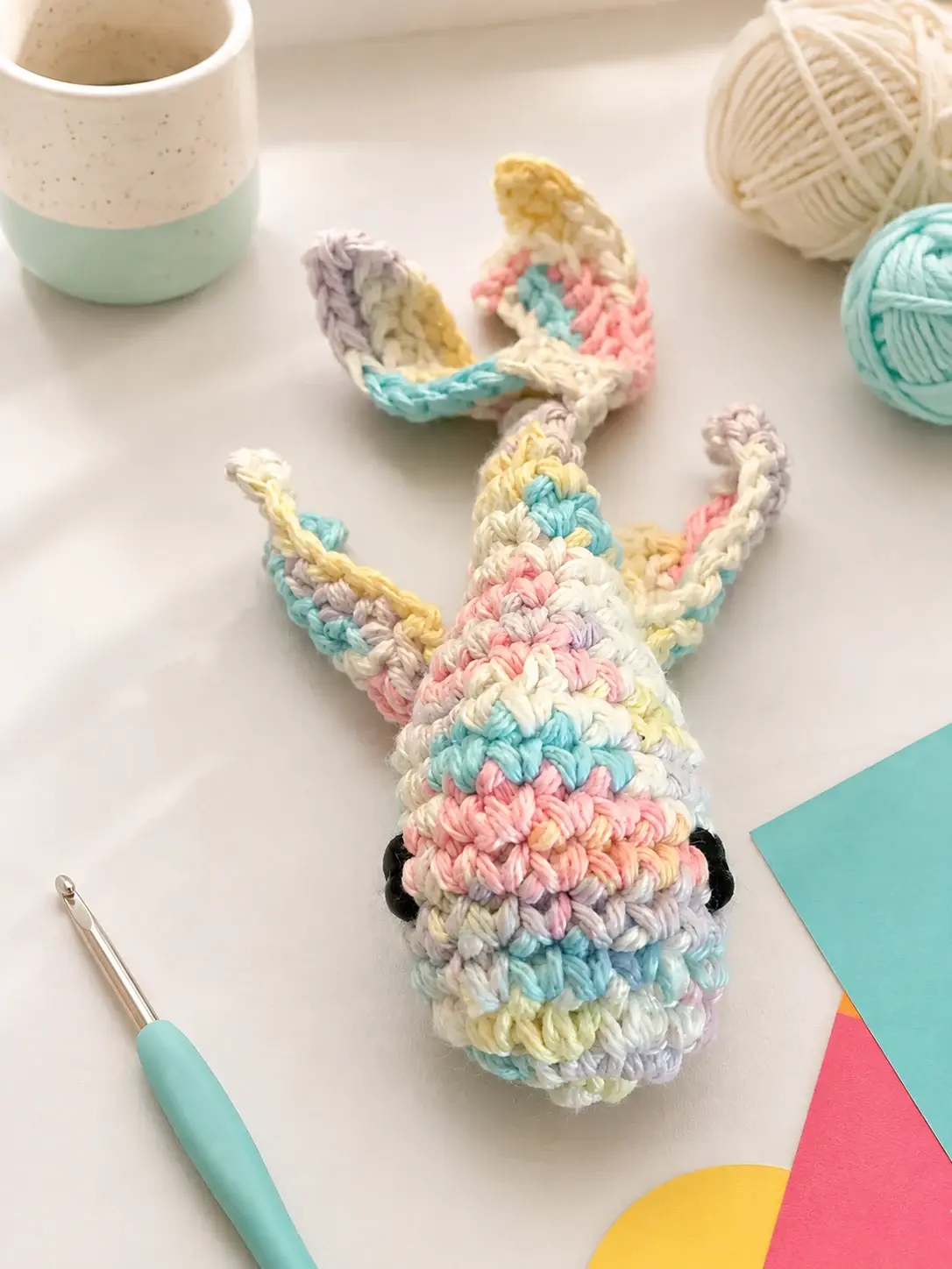 Pastel multicolor hand-crocheted koi fish cat toy in an art studio setting.