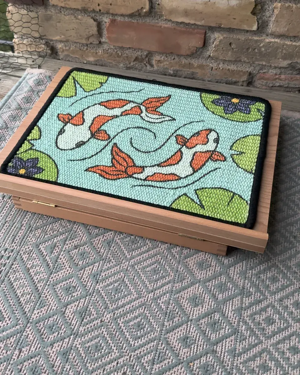 The assembled Koi Scratch Canvas set down flat on a rug, its wooden easel folded underneath.