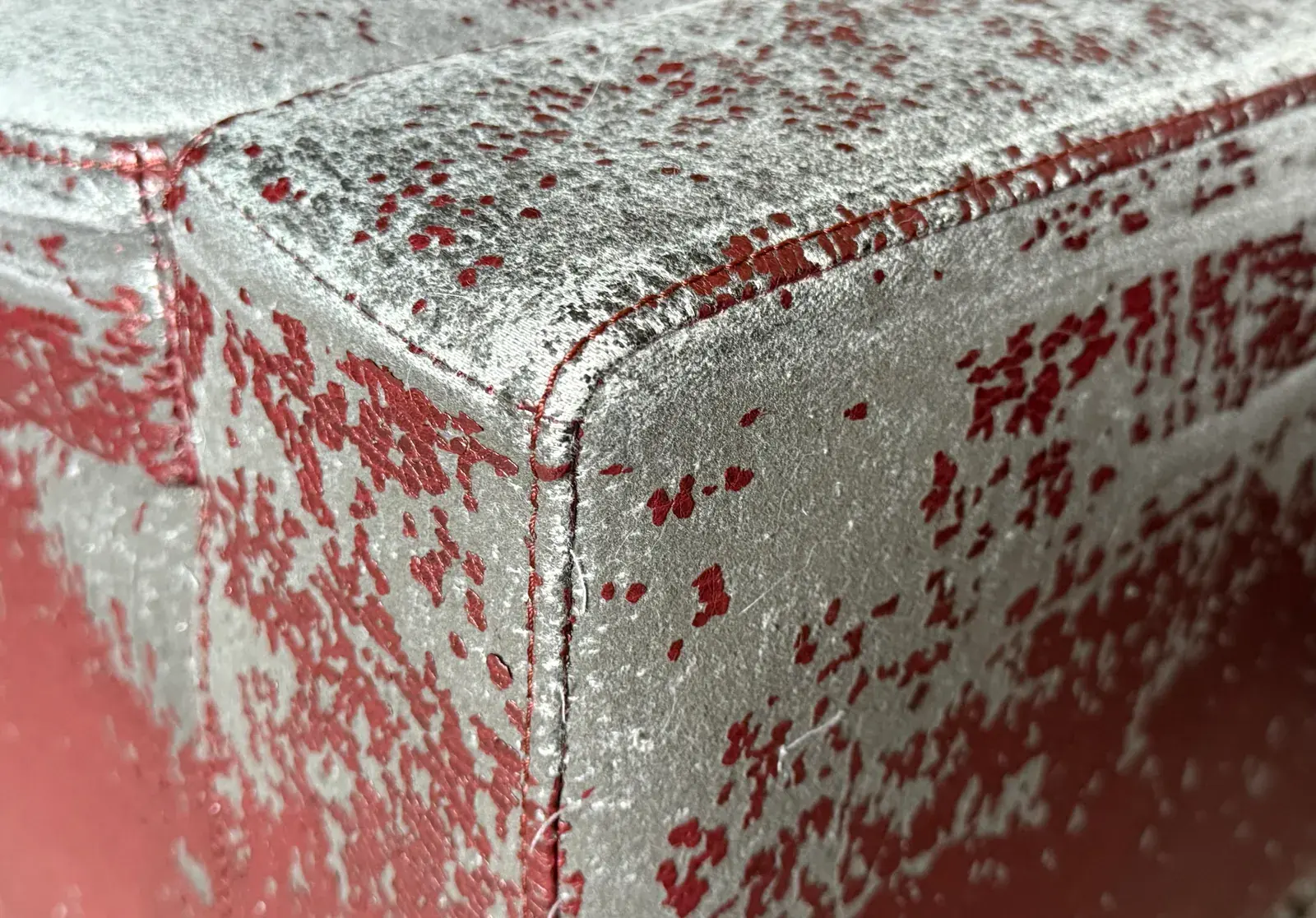 Close view of worn fabric on the ottoman corner Theo scratched.